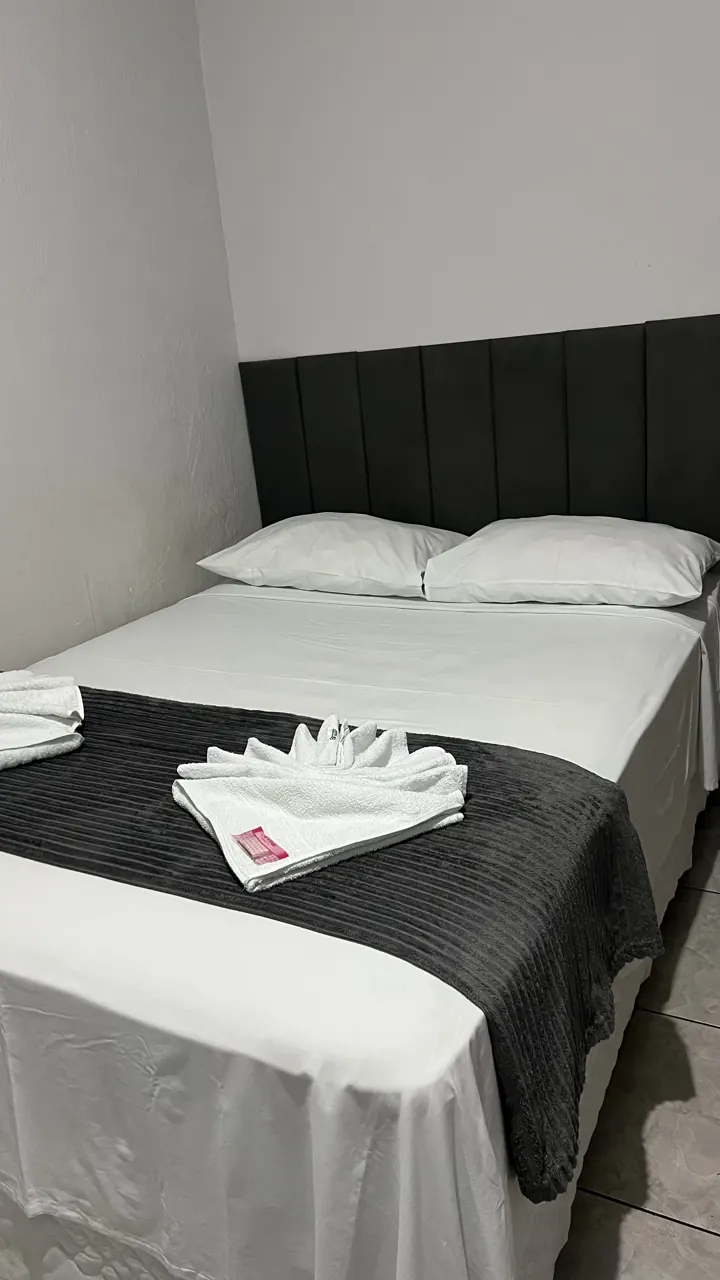 Quarto de casal com roupa de cama branca e manta cinza