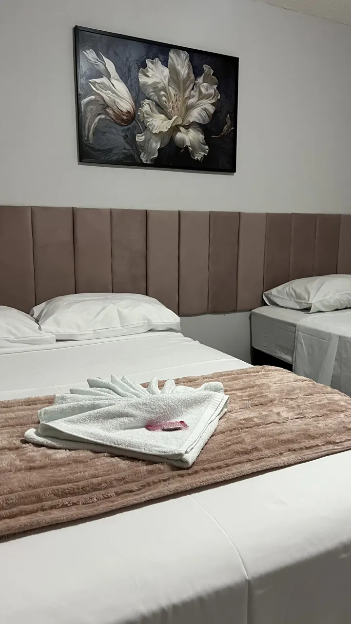 Quarto com cama de casal e cama de solteiro, toalhas dobradas na cama