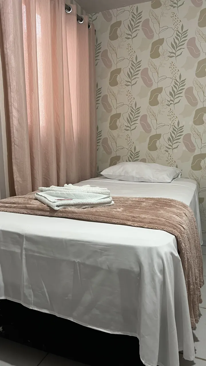 Quarto com papel de parede floral e cama de solteiro arrumada